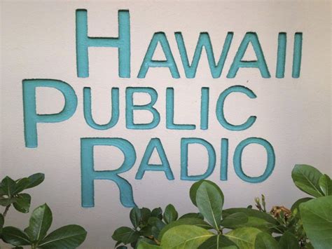 A Sign That Says Hawaii Public Radio On The Side Of A Building With Green Leaves