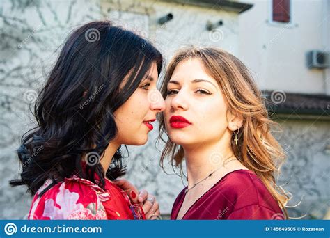 close up of two lesbian friends one blonde and the other brunette are looking at each other