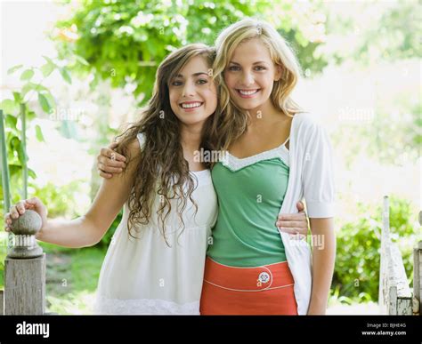 Two Young Women In A Garden With Their Arms Around Each Other Stock