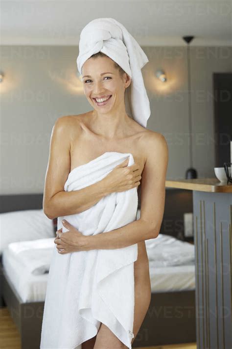 Portrait Of Laughing Woman Wrapped In Towel Standing In Bedroom Stock Photo