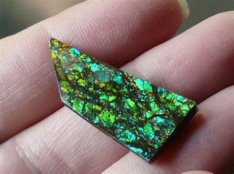 A Piece Of Green And Black Opal In Someones Hand