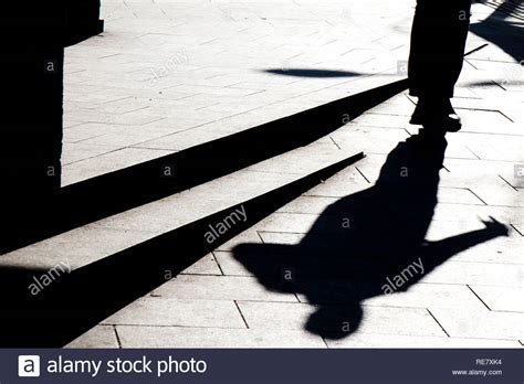 Blurry Silhouette Shadow Of A Man Walking On A City Sidewalk With Steps