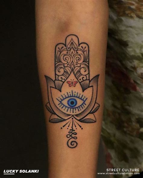 A Tattoo On The Leg Of A Woman With An Evil Eye And Lotus Flower Design