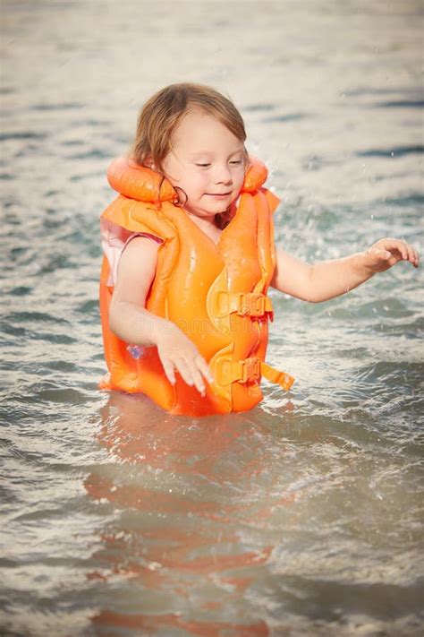 Child Wearing A Yellow Life Jacket In Swimming Pool Stock Photo