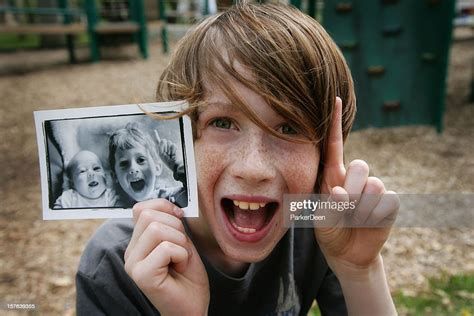 Cute Young Boy Holding Up Photo Of Himself When Younger High Res Stock