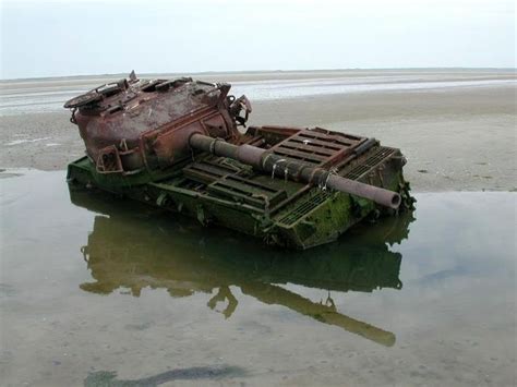 An Old Rusted Out Boat Sitting In The Middle Of Some Water At Low Tide