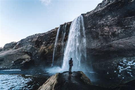 Man Standing On Rock Near Waterfalls During Daytime Photo Free