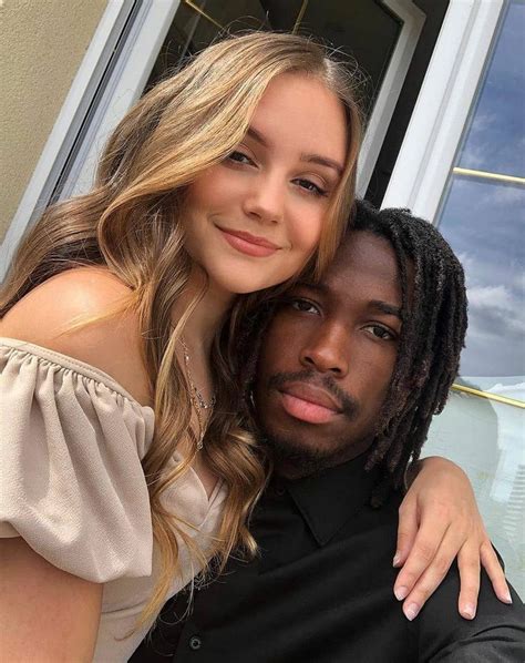 A Young Man And Woman Posing For A Photo In Front Of A Window With