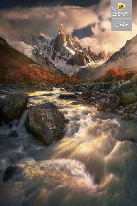 A Painting Of A Mountain Stream With Rocks In The Foreground And Clouds