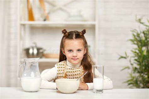 Little Girl Eating Breakfast Cereal With The Milk In The Kitchen