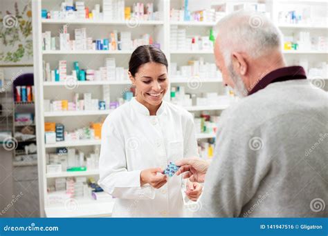 Smiling Young Female Pharmacist Giving Prescription Medication Pills To