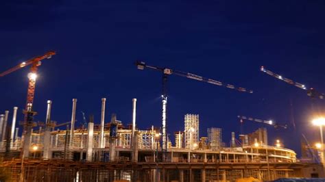Timelapse with cranes working on construction site on night sky ...