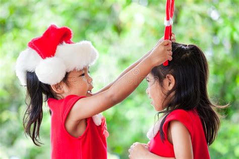 Two Asian Child Girls In Santa Dress Help Each Other To Dress Stock