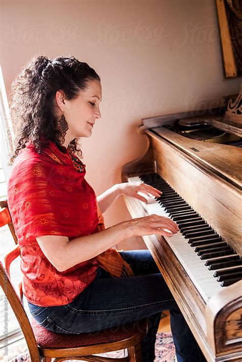 Online piano lessons are always accessible even if you are on the go or when sitting in a chair at home. Middle age woman playing piano at home by Suprijono ...