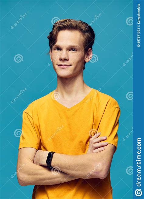 A Guy In A Yellow T Shirt Stands With His Hands Folded On His Chest