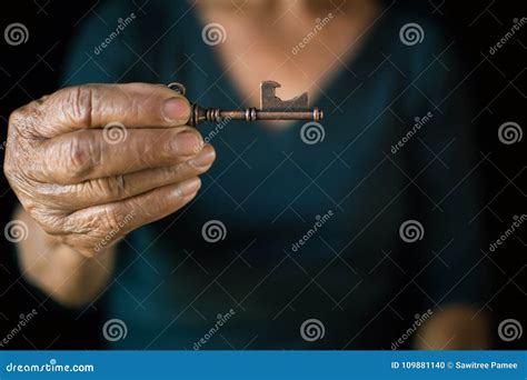 Old Female Hand Holding Vintage Key On Black Background Stock Photo