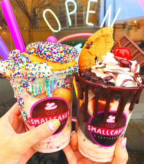 Two Ice Cream Sundaes With Sprinkles And Cookies Are Being Held Up In