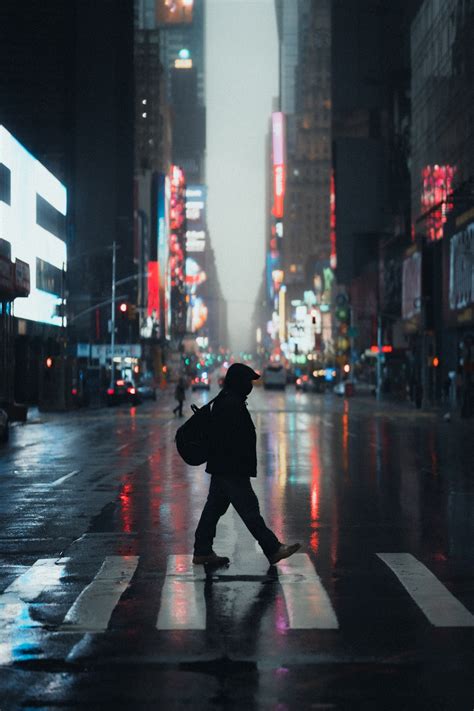 Man In Black Hoodie Walking On Street During Daytime Photo Free