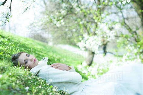 Teenage Girl Lying In Grass Holding Flowers Eyes Closed Stock Photo Dissolve