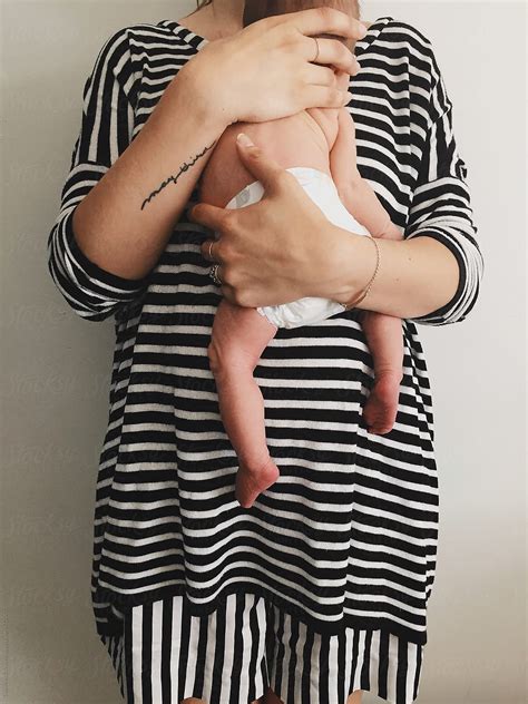 Mom In Stripes Holding Newborn Baby By Stocksy Contributor Pink