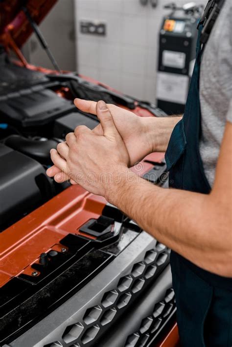 Cropped Shot Of Repairman Standing At Car With Opened Cowl Stock Photo