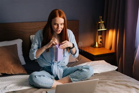 Cheerful Redhead Young Woman Having Video Call On Laptop Via Webcam In Bedroom Sitting At Bed
