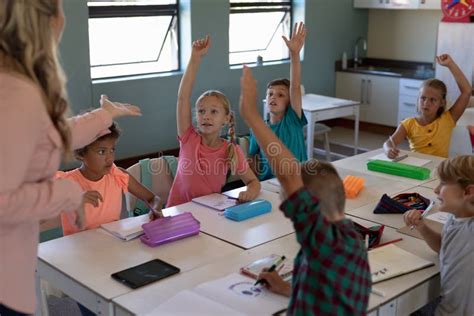 Group Of Schoolchildren Raising Their Hands In An Elementary School