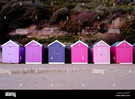 A Row Of Brightly Coloured Beach Huts On A Sandy Seafront In