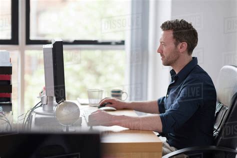 Man Working At Computer On Office Desk Stock Photo Dissolve
