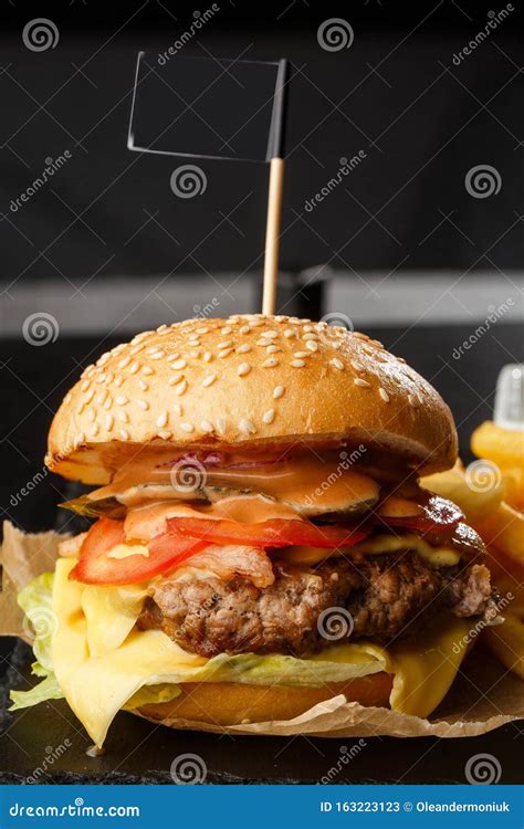 Big Single Cheeseburger With French Fries Isolated On Black Background