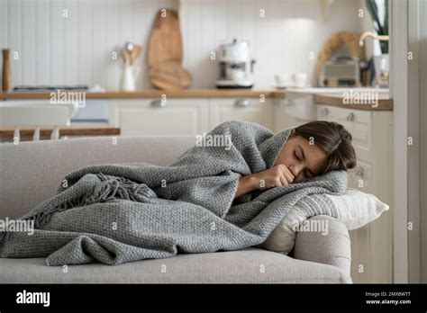 Sick Girl Child Covered With Blanket Lying On Sofa At Home Coughing