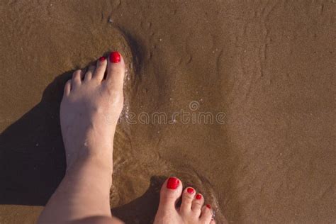 Feet Of Woman With Nails Painted Red On The Sand Of The Sea Stock Image