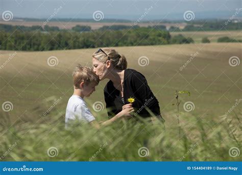 Beautiful Blonde Mother Kisses Her Sweet Son Who Gives Flower Stock