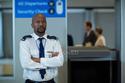 Portrait Of Airport Security Officer Standing With Arms Crossed In