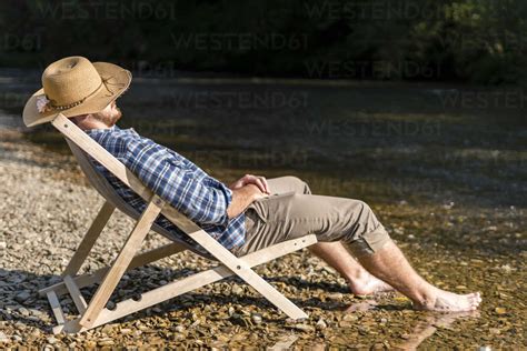 Mann Entspannt Sich Im Strandkorb Am Flussufer Lizenzfreies Stockfoto