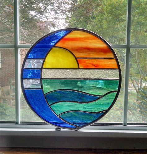A Stained Glass Sun Catcher Sitting On Top Of A Window Sill