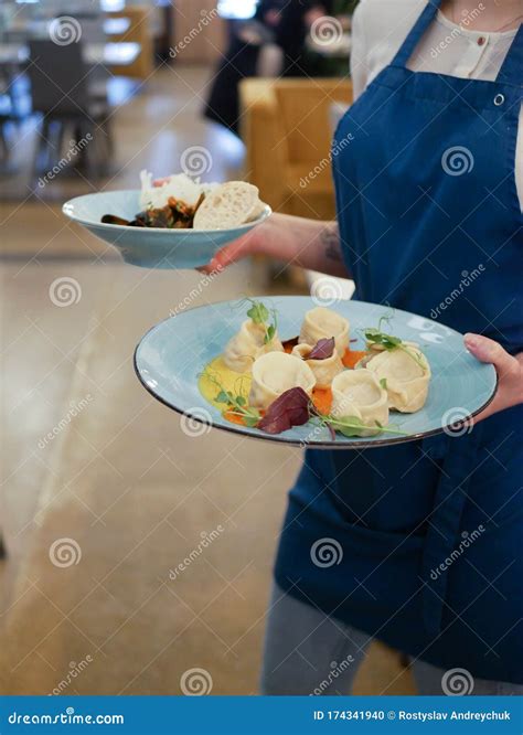 Waitress In A White Uniform Holding A Plate With Asian Food In A