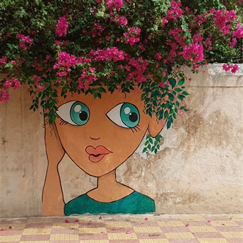 A Painting On The Side Of A Building With Flowers Growing Out Of Its Head