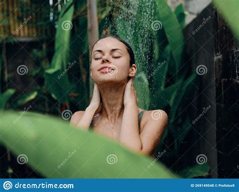 A Woman Takes A Shower And Washes Her Head And Hair Outdoors Against