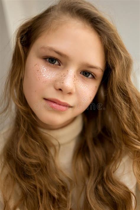 portrait of serious girl with golden star freckles and long hair looking at camera soft focus