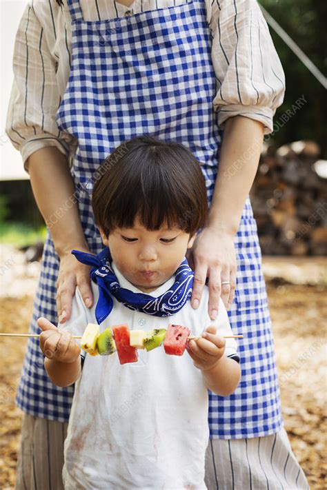 Woman And Child Holding Skewers With Fresh Kiwi And Melon