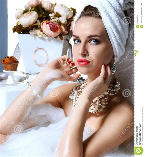 Luxury Fashion Woman In Hotel Spa Lying In Bath Tub With Bouquet Of