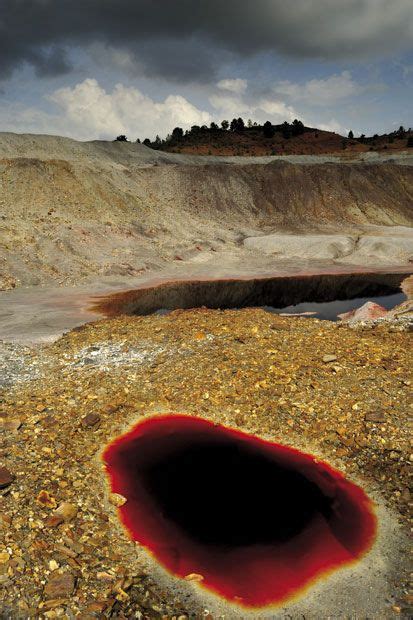 A Large Hole In The Ground With Red Paint On Its Surface And Dark