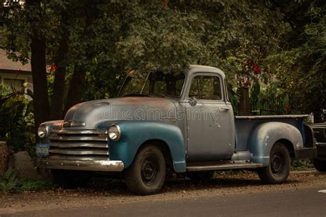 Classic Chevy Truck Parked In A Country Neighborhood Under A Green Tree