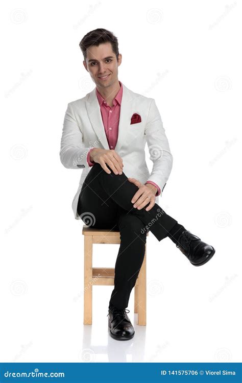 Relaxed Young Elegant Man Is Sitting With Legs Crossed Stock Photo