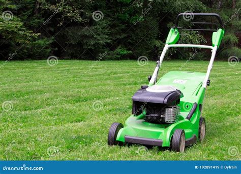 A Green Lawnmower In The Garden A Lawn Mower On The Green Grass Stock