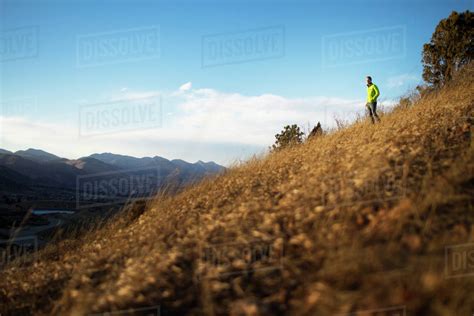 Man Standing On Hill Overlooking Valley Stock Photo Dissolve
