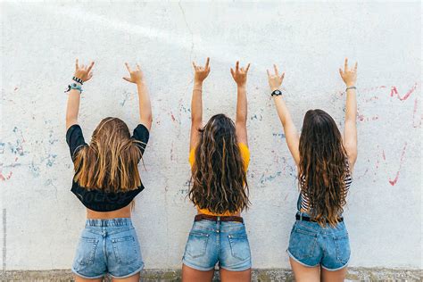 Three Naughty Teen Girls Making The Rock Sign Giving Back To Camera Del Colaborador De Stocksy