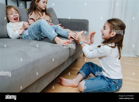 Side View Of A Girl Conducting Tickling Competition Between Siblings