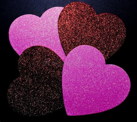 Four Different Colored Glittery Hearts On A Black Background Stock